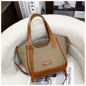 Détail d'un sac cabas en cuir marron et tissu beige avec bandoulière réglable et logo