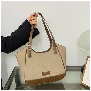 Detalle de las costuras de lona beige y cuero marrón en el bolso tote con logo