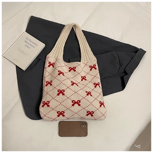 Detail view of cream knit tote with red bow pattern and thick weave texture