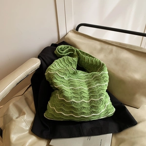 Green and white woven hobo bag with wave patterns shown in a stylish lifestyle setting