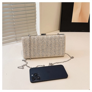 Pochette in paglia con catena argento, mostrata accanto a uno smartphone per le dimensioni