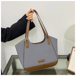 Detalle de bolso tote de lona a rayas con base de cuero sintético marrón y asas