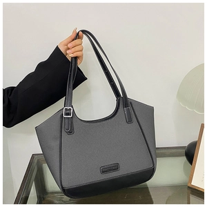 Detalle del bolso tote de lona gris con adornos de cuero negro y hebillas de metal