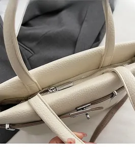 Detailed close-up of cream lychee texture leather tote with silver metal zipper closure