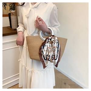 Detailed texture of hand-woven straw tote bag with round white handle and printed silk scarf