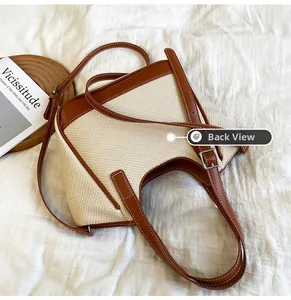 Vue à plat d'un sac cabas tissé beige avec garniture en cuir brun et boucles argentées