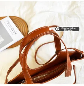 Détail des poignées en cuir marron et de la texture toile sur un grand sac cabas
