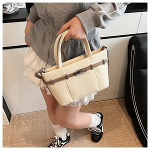 Detail of creamy white tote bag featuring lychee texture leather and brown belt accent