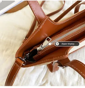 Détail de la fermeture éclair en métal argenté sur un sac en cuir brun et tissu tissé