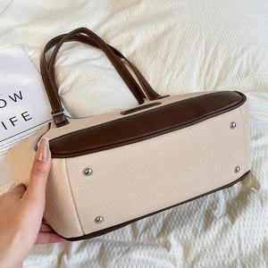 Detalle del bolso tote de lona con fondo de cuero marrón y remaches metálicos de base