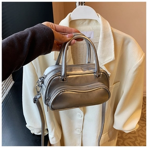 Detail of silver metallic mini crossbody bag featuring dual zippers and Y2K aesthetic