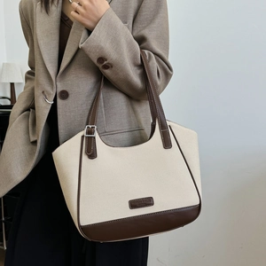 Detalle de bolso tote de lona crema y cuero marrón con hebilla plateada ajustable