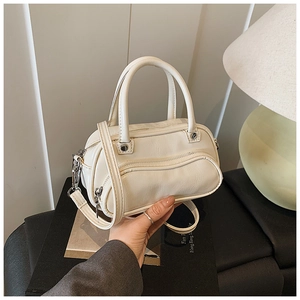 Detail view of cream PU leather handbag featuring silver zippers and adjustable strap