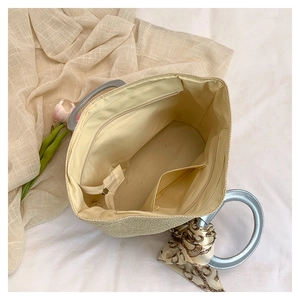 Macro view of woven handbag interior with zip pocket, scarf detail, and ring handles