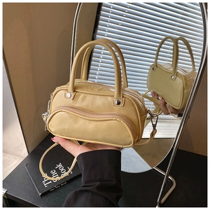 Detail of beige shoulder bag with unique wavy zipper pocket and metallic buckles