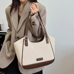 Detalle de bolso tote de lona beige con ribete de cuero marrón y correa de hombro en modelo
