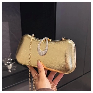 Detail view of a gold evening clutch featuring a rhinestone buckle and chain strap