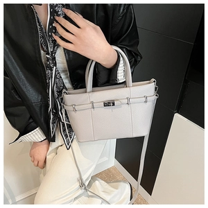 Close-up of minimalist light gray pebbled leather tote bag with metallic belt buckle detail