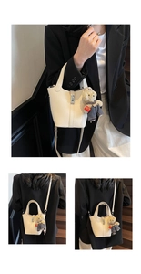 Detail of off-white lychee leather bucket bag with silver lock and bear pendant