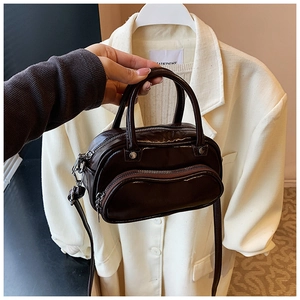 Detail of a dark brown glossy mini handbag with wave zipper pocket and slim strap