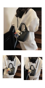 Detail of black lychee grain leather bucket bag with silver lock and bear pendant