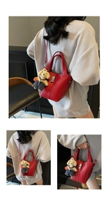 Detail of red litchi grain leather bucket bag with metal lock and cute bear charm