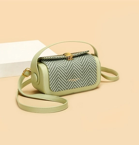 Detailed shot of mint green leather bag with herringbone weave flap and golden clasp