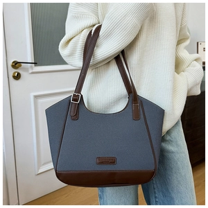Detalle del bolso de lona azul con adornos de cuero marrón y hebillas metálicas de ajuste