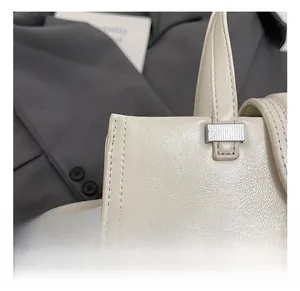 Détail macro du sac en cuir blanc crème montrant les ferrures argentées et la couture