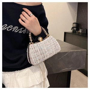 Detail of white tweed evening clutch with crystal handle and pearl clasp on model