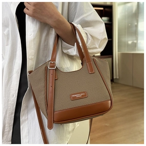 Détail du sac cabas en cuir marron et tissu beige à chevrons porté par un mannequin