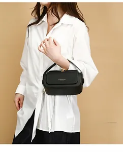 Detail of black leather shoulder bag featuring woven flap and golden rotating metal clasp