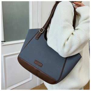 Detalle del bolso tote de lona azul con ribetes de cuero marrón y hebilla de metal