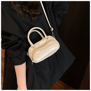Close-up of a white glossy patent leather crossbody bag with silver hardware and dual handles