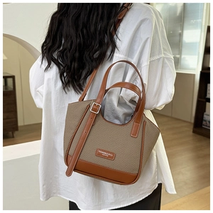Détail du sac cabas en sergé et cuir avec bandoulière réglable et écusson de logo