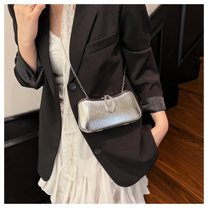 Close-up of a silver hard-shell evening bag with rhinestone buckle and chain strap