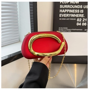 Detail of red velvet evening bag featuring a large gold C-clasp and thin metal chain