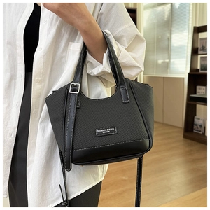 Détail d'un sac cabas tissé noir avec coutures contrastées et poignée en cuir