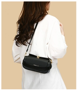 Detail of black crossbody box bag with golden metal buckle and fine grain leather texture