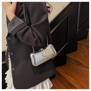 Detail of silver metallic evening clutch featuring a rhinestone lock and fine chain strap