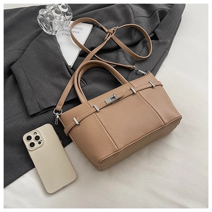 Detail of brown lychee grain leather tote featuring a silver metal twist lock and strap