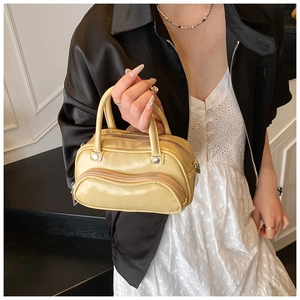 Detail of yellow glossy leather crossbody bag with wavy zipper and metallic hardware