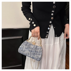 Close-up of blue tweed handbag with pearl clasp and golden ring handle detail