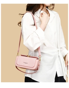 Detail of pink leather crossbody bag with herringbone fabric flap and gold buckle