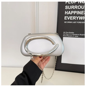 Close-up of a silver metallic evening bag featuring a large circular metal buckle and chain
