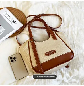 Détail du sac cabas en paille tissée avec anses en cuir marron et bandoulière longue