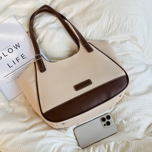 Detalle del bolso tote de lona con base de cuero marrón y tachuelas de protección