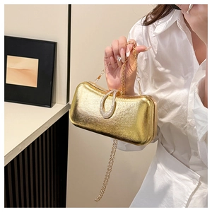 Detail of gold evening clutch bag featuring metallic texture and rhinestone ring clasp