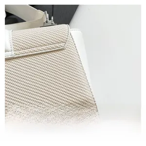 Détail du tissu tissé beige avec garniture en cuir blanc et boucle argentée sur le sac
