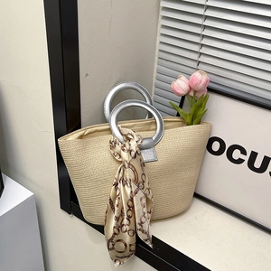 Beige woven handbag with silver round metal handles and decorative silk scarf accessory